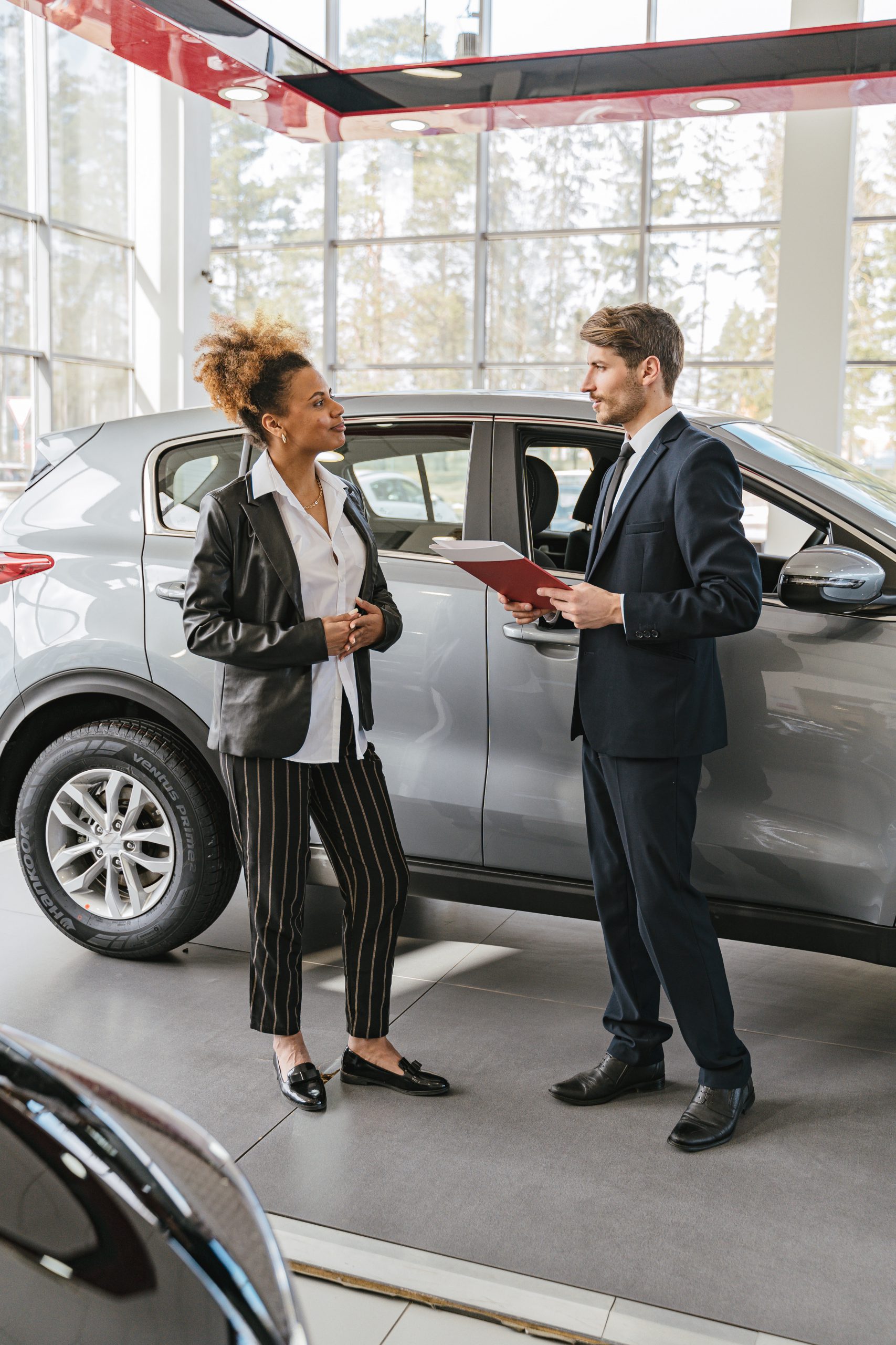 Two people having a discussion next to a parked car.
