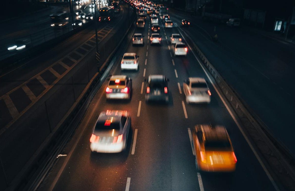 A photo of cars driving down the road at night.