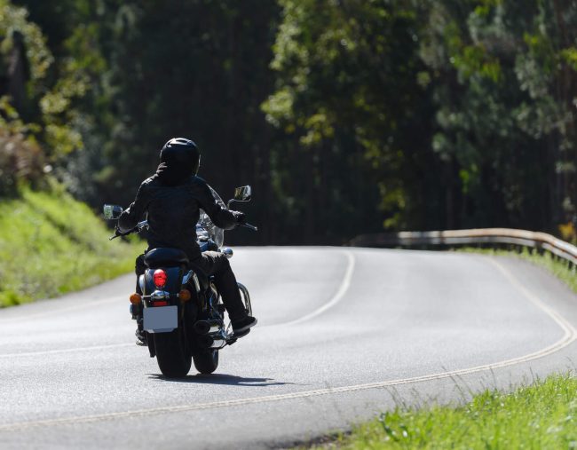 Motorcycle rides down the road.